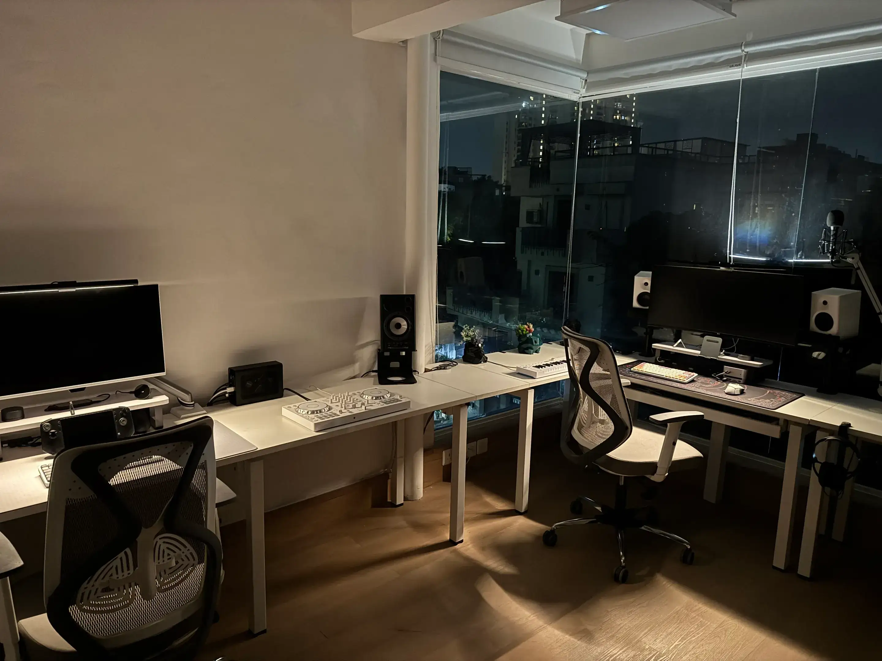 The wraparound desk after dark, city through the glass on two walls